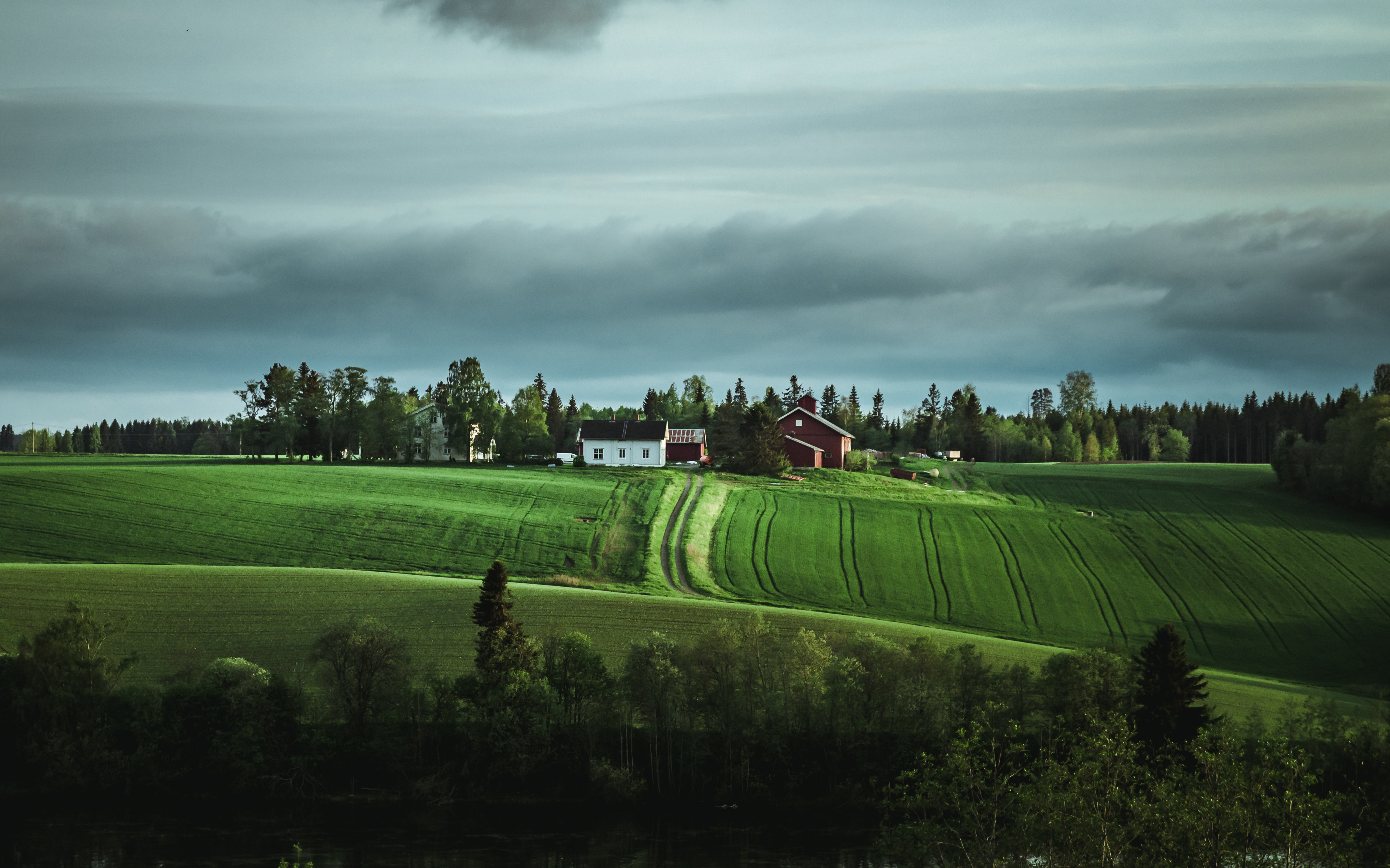 Fotografi av en norsk gård omringer av jorder og skog